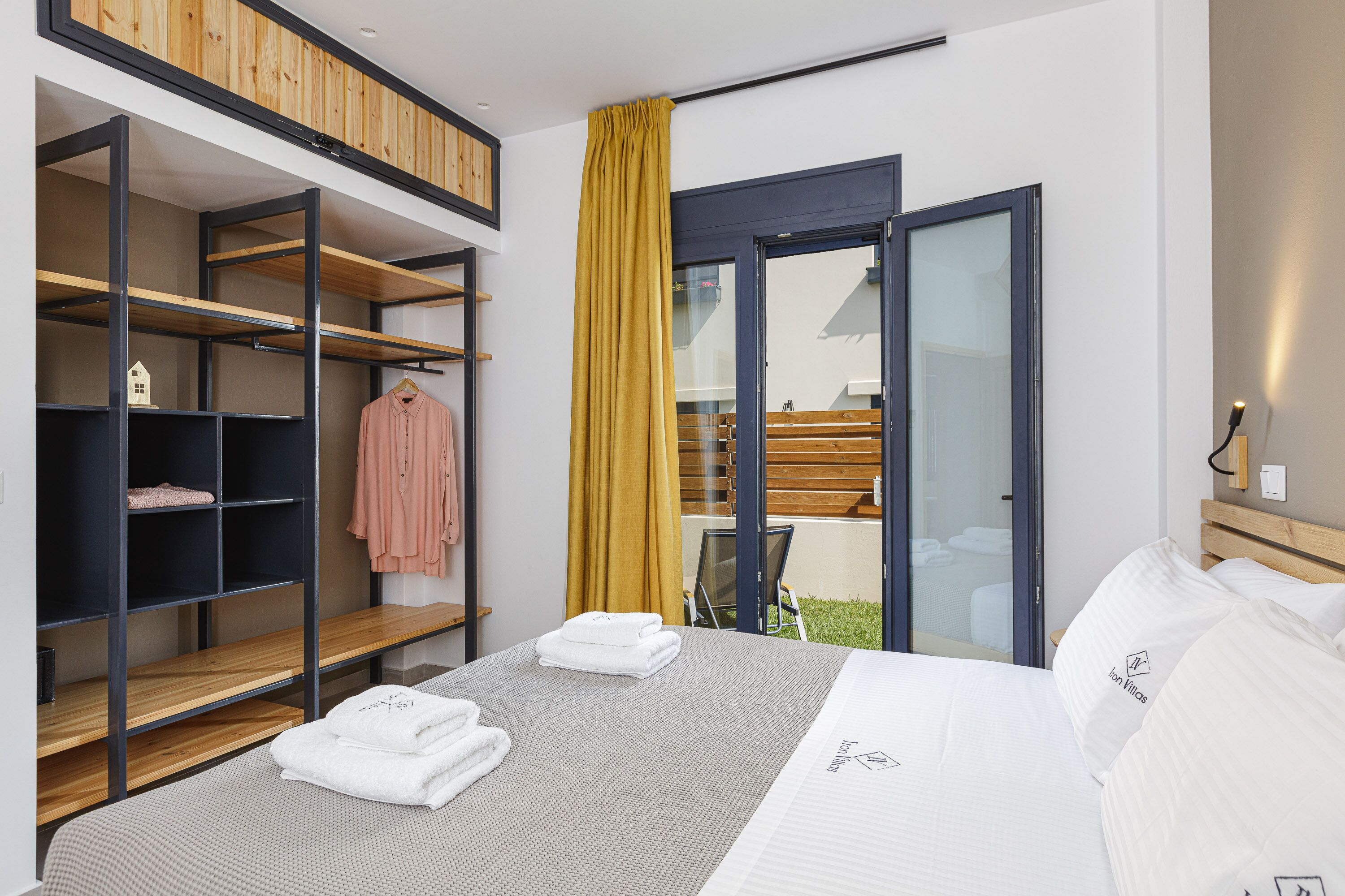 Et moderne hotelværelse med seng, indbygget skab, balkon med gult gardin og udsigt ud