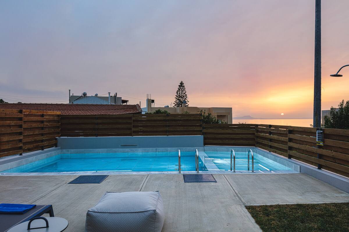 Ein Pool auf dem Dach mit Blick auf den Sonnenuntergang, einer Holzterrasse und einer Lounge-Bereich.