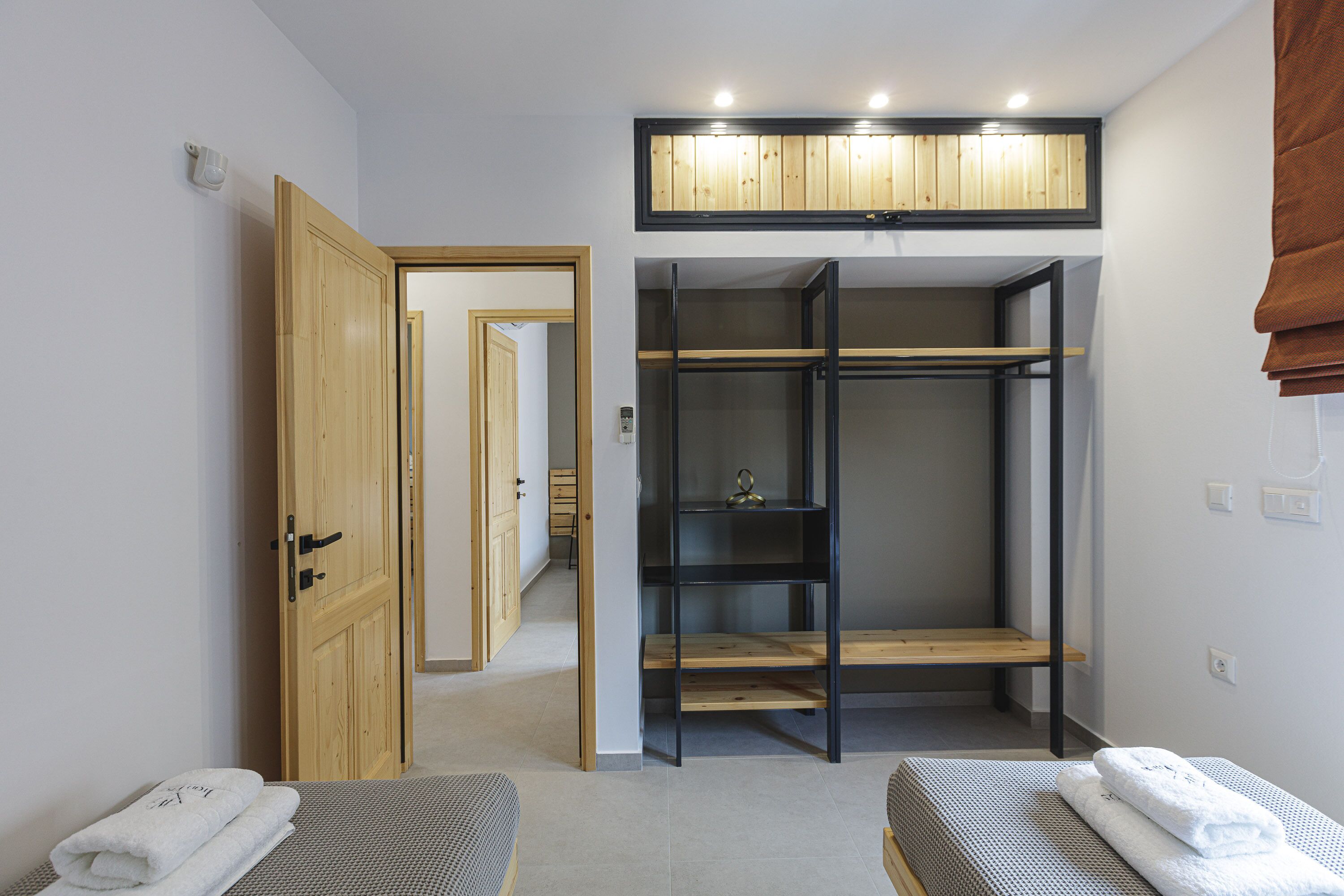 A bedroom with a wooden wardrobe, a bed, and a small seating area.