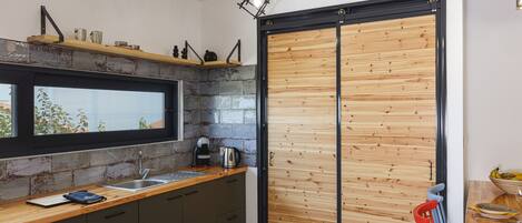 A modern kitchen with a large window, a sink, and a wooden door.