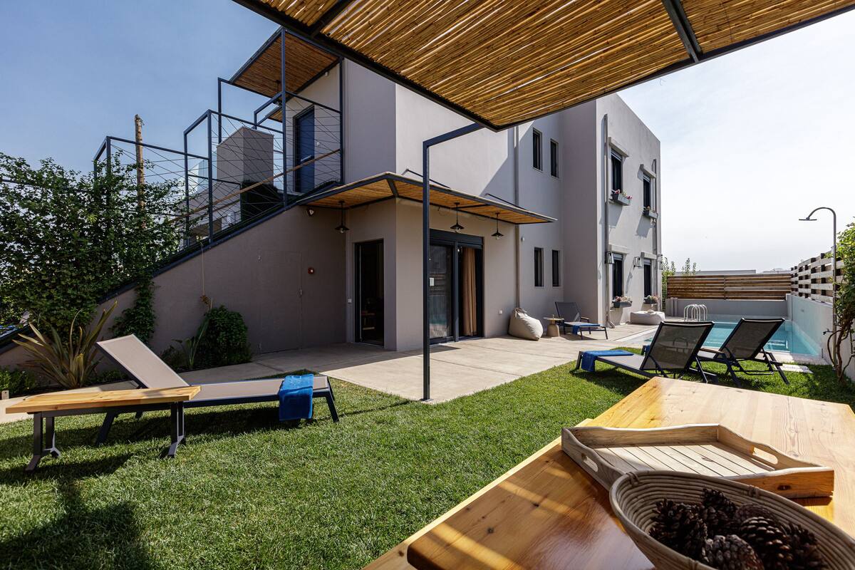 Ein modernes Haus mit geräumiger Terrasse, Gartenmöbeln und einem Pool.