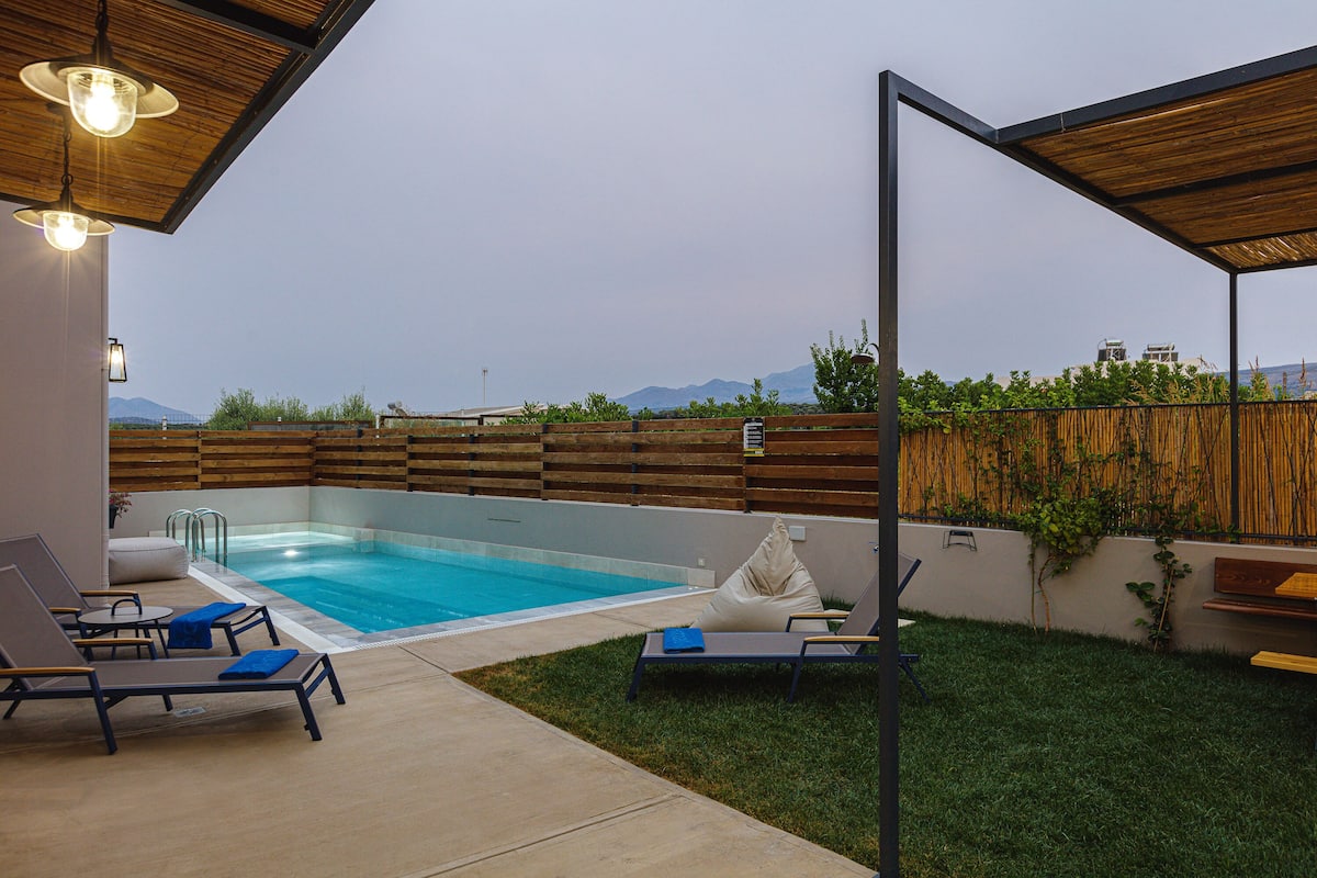 Ein Garten mit Swimmingpool, Liegestühlen und einer Holzpergola.