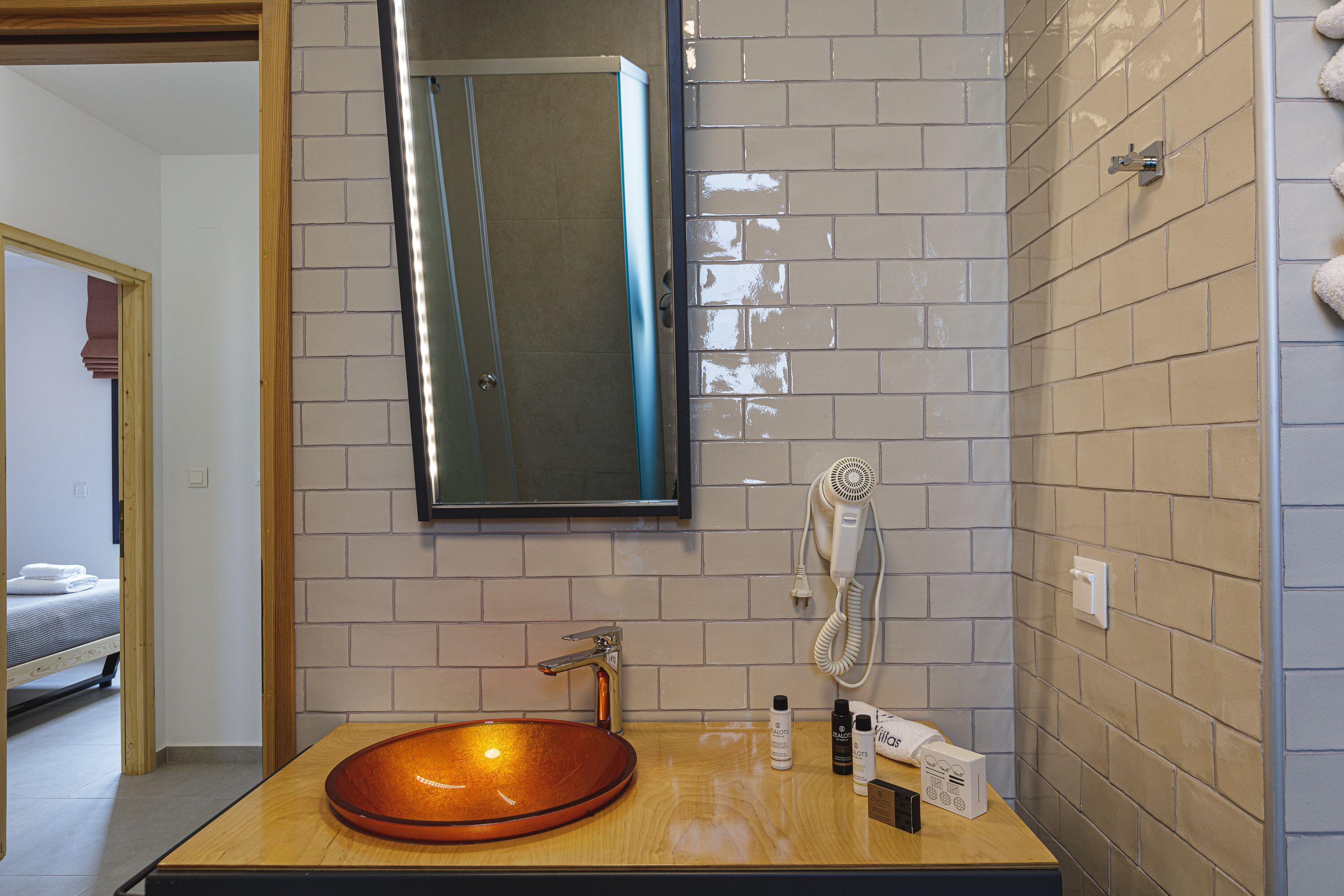 Une salle de bain avec un meuble-lavabo en bois, un lavabo rond, un miroir et un porte-serviettes.