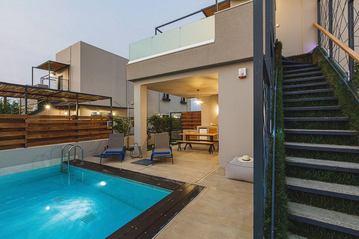 Ein moderner Poolbereich im Freien mit Holzterrasse, Liegestühlen und einer Treppe zu einer erhöhten Ebene.