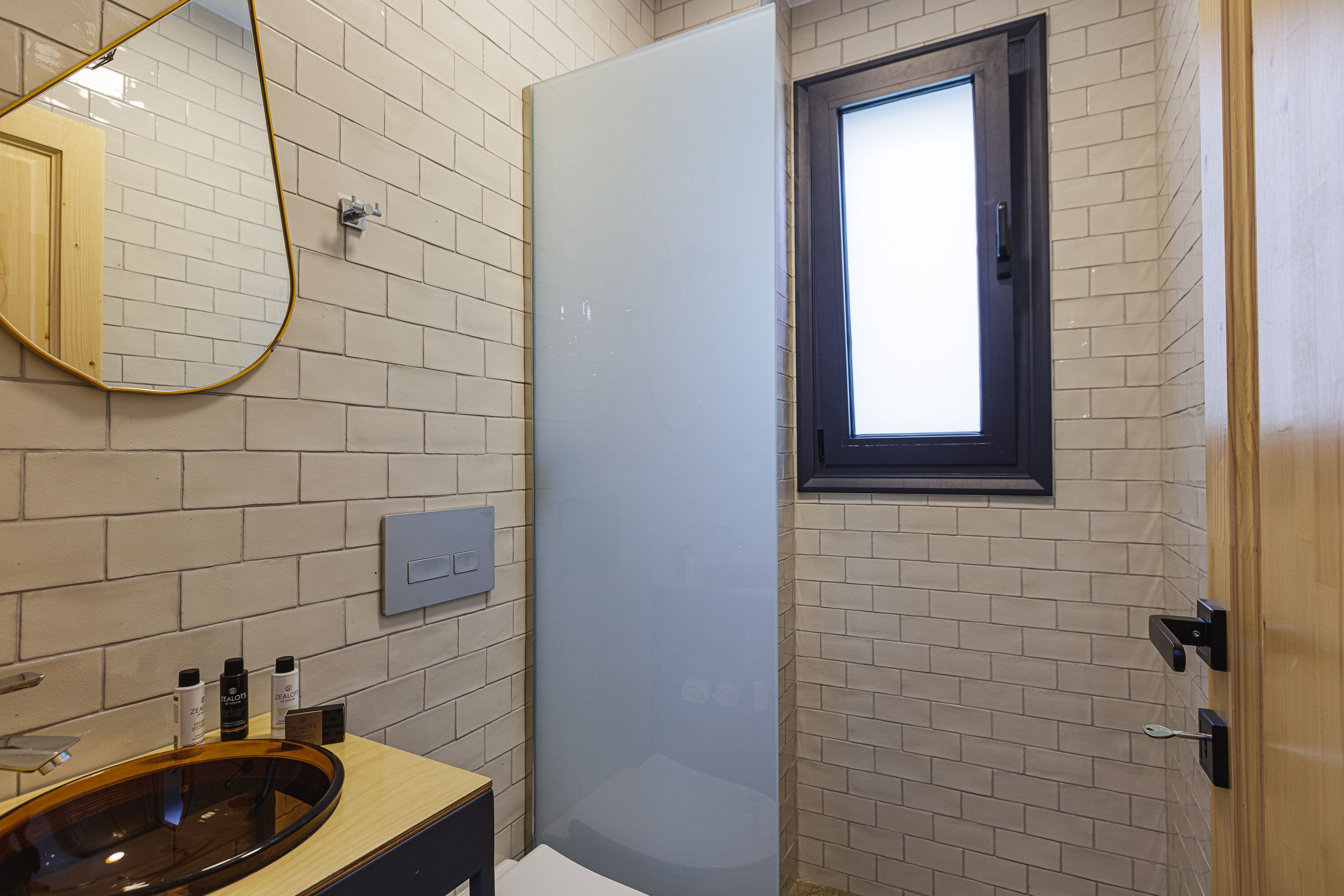 A bathroom with a wooden vanity, a mirror, and a window.