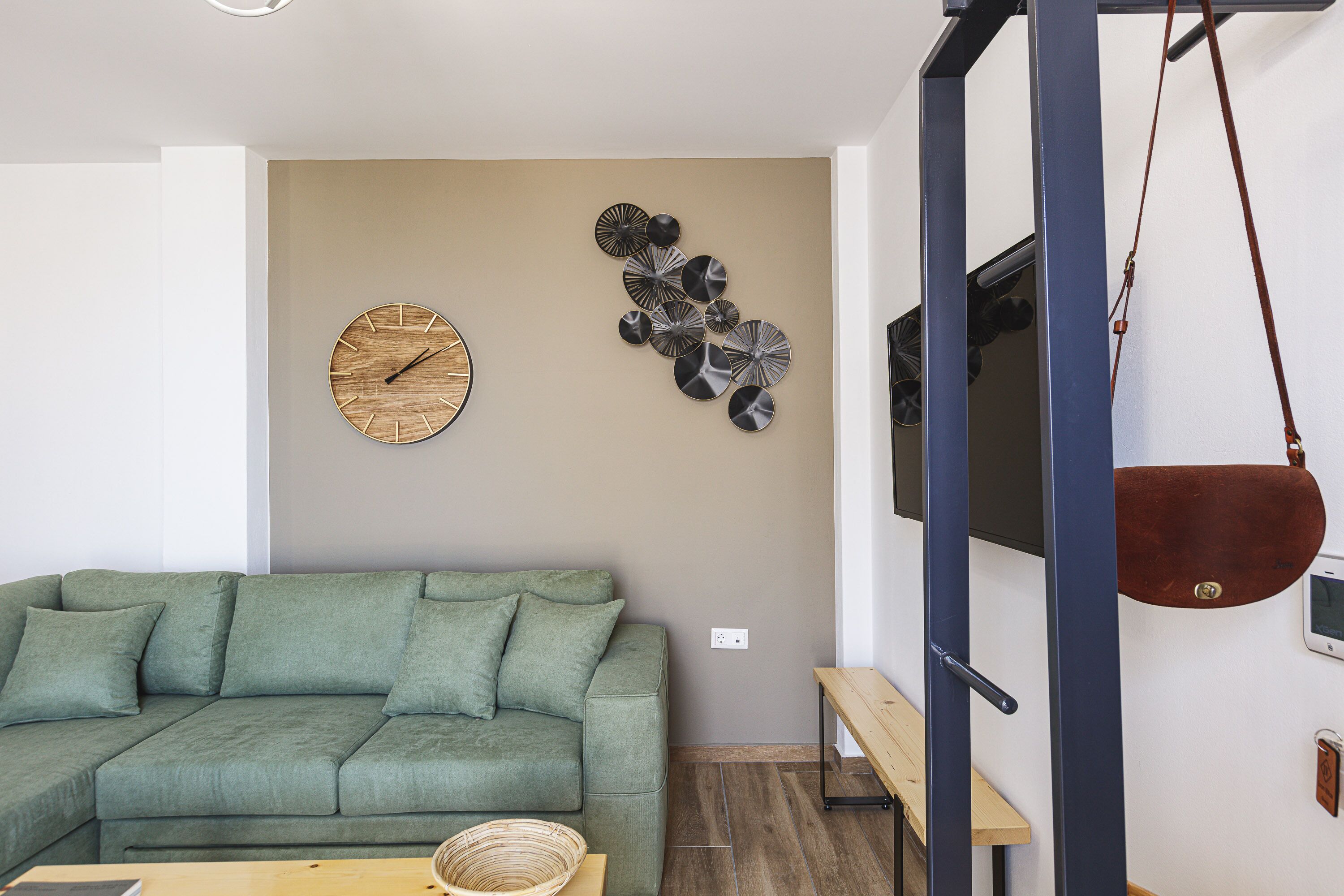 Ein modernes Wohnzimmer mit einem grünen Sofa, einer Holz-Uhr und abstrakter Wandkunst.