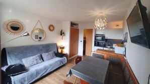 En kompakt opholdsstue med sofa, spisebord og tekøkken.