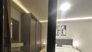 A modern bedroom with a large bed, a bedside table, a nightstand, and a wall-mounted TV. - JRE Cozy Rooftop Near Al Services-23 (Amman)