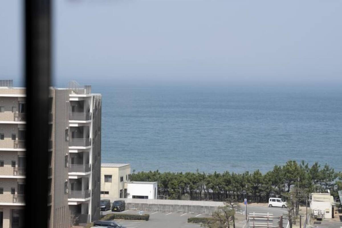 A view of a coastal area with a building, a parking lot, and the sea.