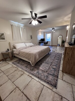 A bedroom with a bed, a ceiling fan, a desk with a chair, a TV, and a large mirror. - Cozy home near Lake Michigan with Smart TVs, fast Wi-Fi, and rustic charm. (Michigan City)