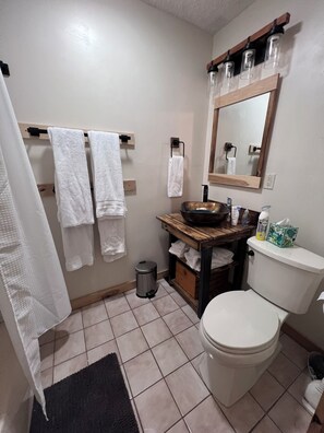 A bathroom with a toilet, sink, mirror, and towel rack. - Cozy home near Lake Michigan with Smart TVs, fast Wi-Fi, and rustic charm. (Michigan City)
