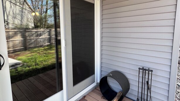 Eine überdachte Veranda mit einer Schiebetür, einem schwarzen Terrassenheizer und einem Werkzeugregal aus Metall.