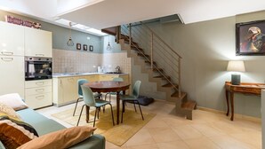Un espacio habitable compacto con kitchenette, comedor y una escalera.