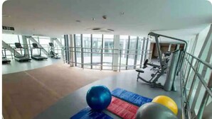 Un gimnasio con cintas de correr, pelotas de ejercicio y un amplio ventanal.