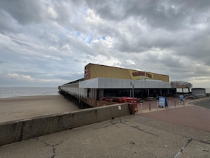 Un bâtiment situé au bord de l’eau, appelé « Walton Pier », avec une jetée qui s’avance dans l’eau, des bancs et un panneau indiquant « PÊCHE ».