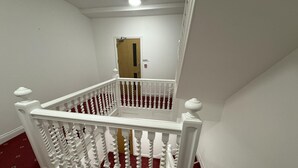 A staircase with white balusters and a red carpeted floor. - Beautiful 2 Bed Apartment in Walton on the Naze (Walton on the Naze)