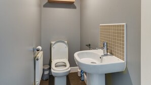 A small bathroom with a toilet, a sink, and a radiator. - Charming 2-bed House in Middleton Manchester (Manchester)