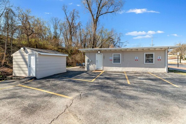 A small building with a garage, a parking lot with marked spaces, and a clear sky.