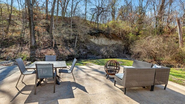 An outdoor patio with a table and chairs, a wicker sofa, and a fire pit. - Honky Tonk Hideaway (Saint Charles)