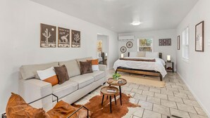 A bedroom with a bed, a sofa, a small table, and a cowhide rug. - Honky Tonk Hideaway (Saint Charles)