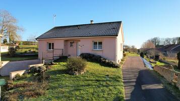 A single-story house with a tiled roof, a front door, and a small porch.