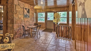 Ein rustikales Interieur mit Steinwänden, Holzbalkendecke und einem Essbereich mit Stühlen und Tisch.