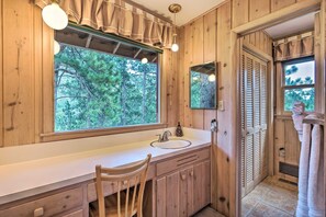 A wooden bathroom with a large window, sink, and mirror. - Cozy Mountain Retreat at the Base of Pikes Peak! (Cascade-Chipita Park)