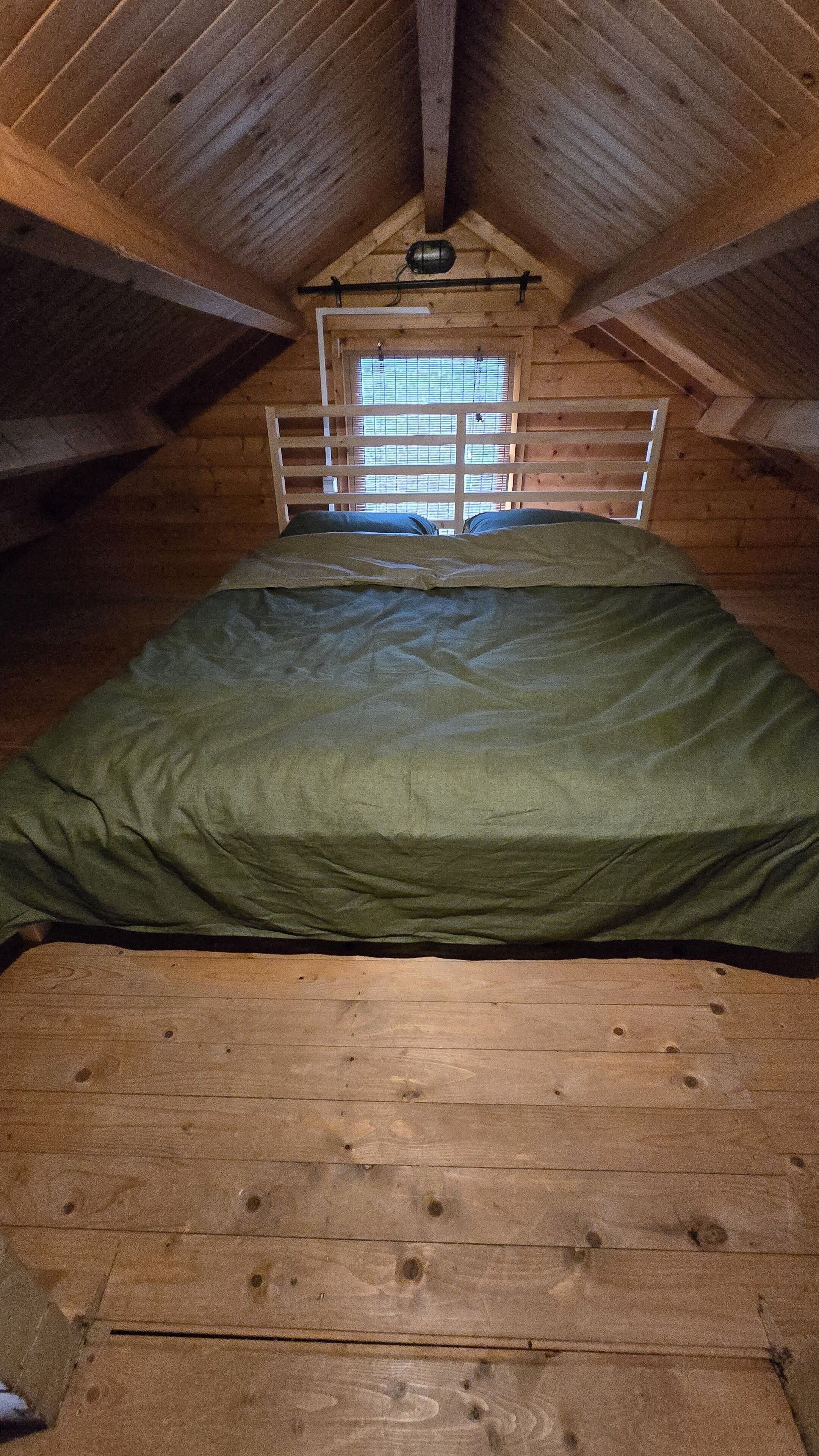 Ein kleines Schlafzimmer im Dachgeschoss, mit Etagenbett, einem Fenster mit Jalousien und schrägem Dach.