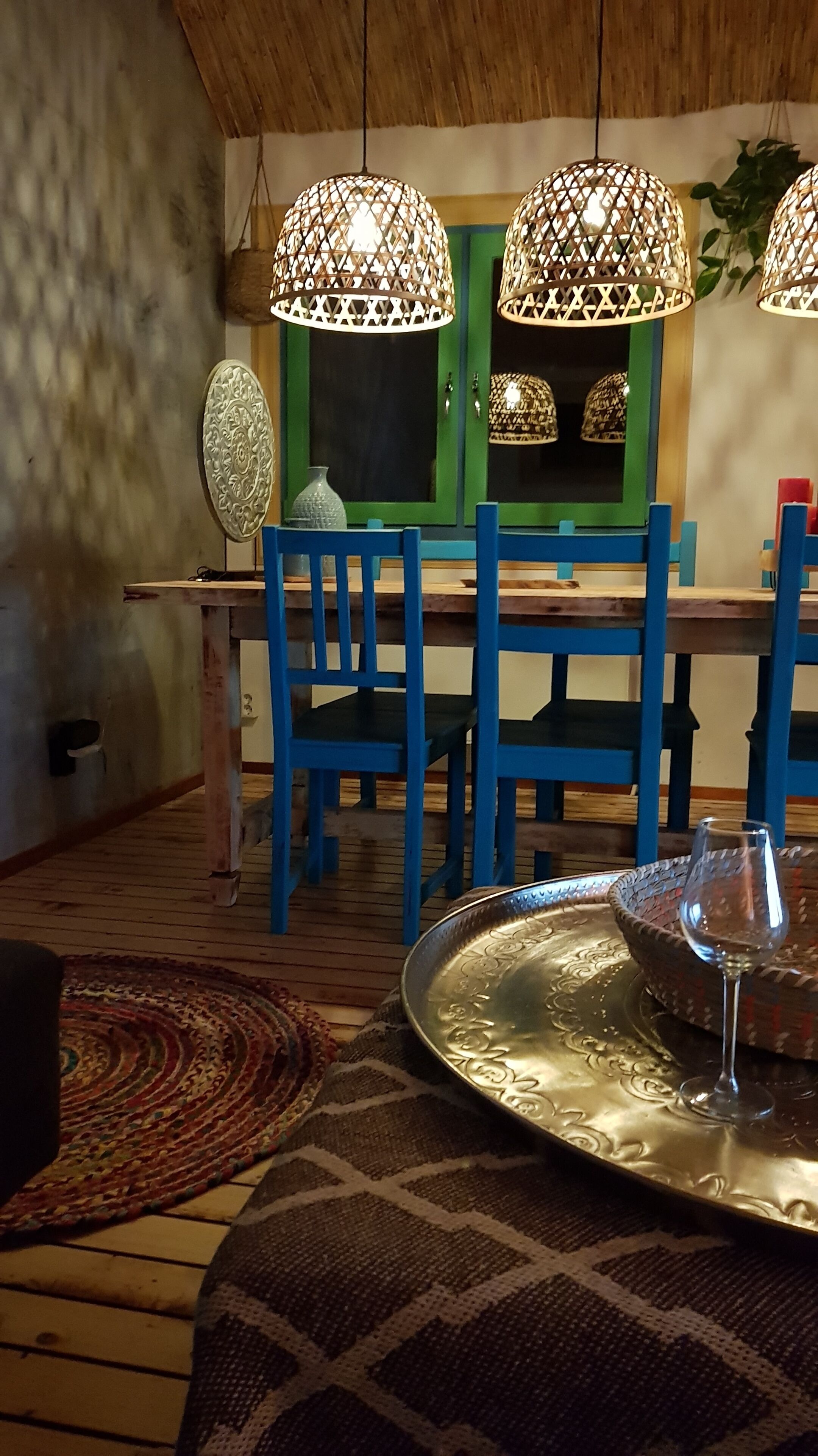 Un comedor con mesa de madera, sillas azules y una lámpara colgante.