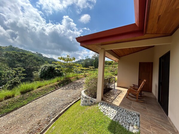 Un espacio al aire libre cubierto con una jardinera de piedra, un banco de madera y vistas a un paisaje montañoso.