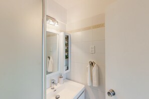 Une salle de bain avec un lavabo blanc, un miroir et un porte-serviettes.