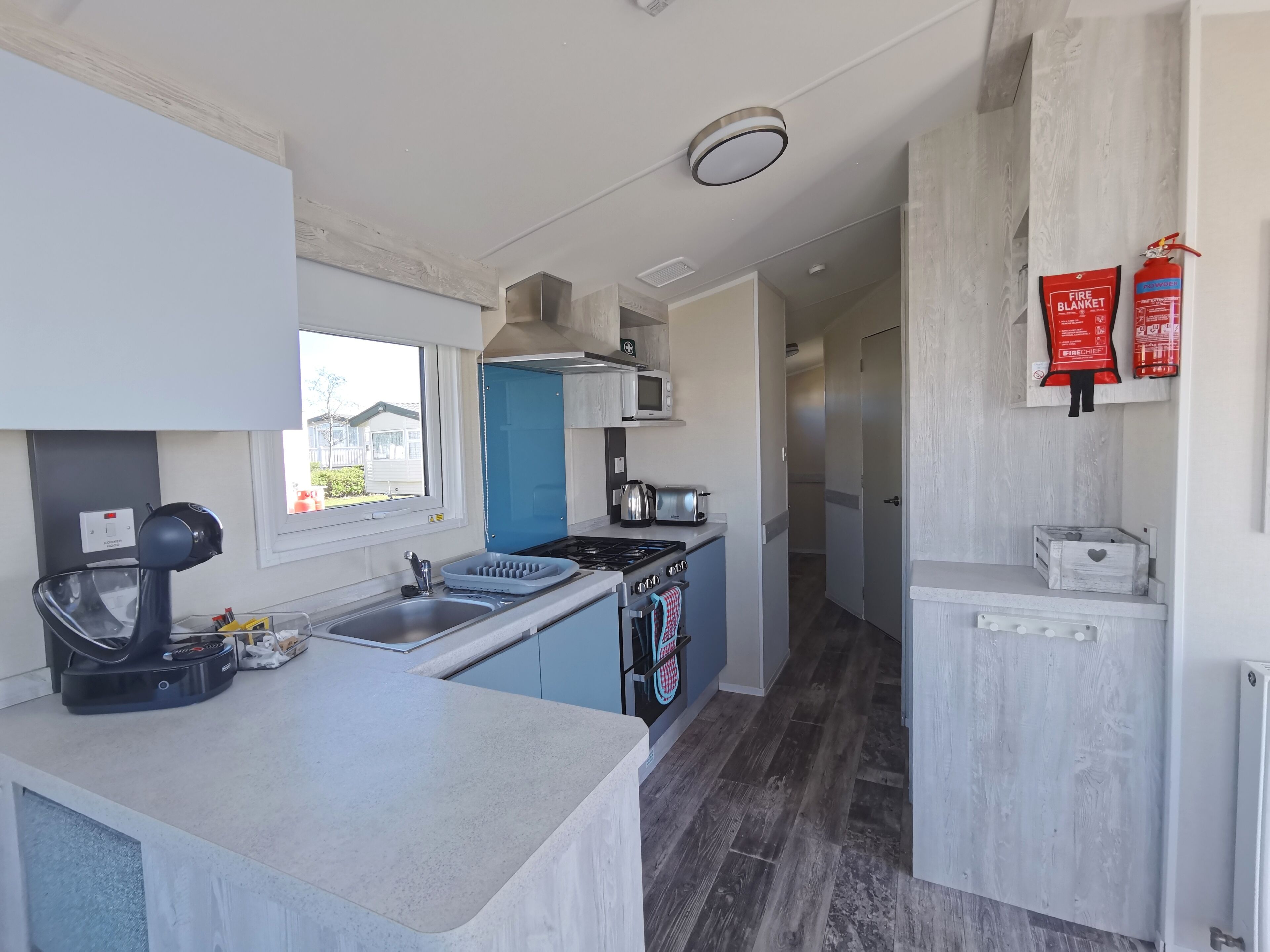 A modern kitchen with a central island, stainless steel appliances, and a blue door.