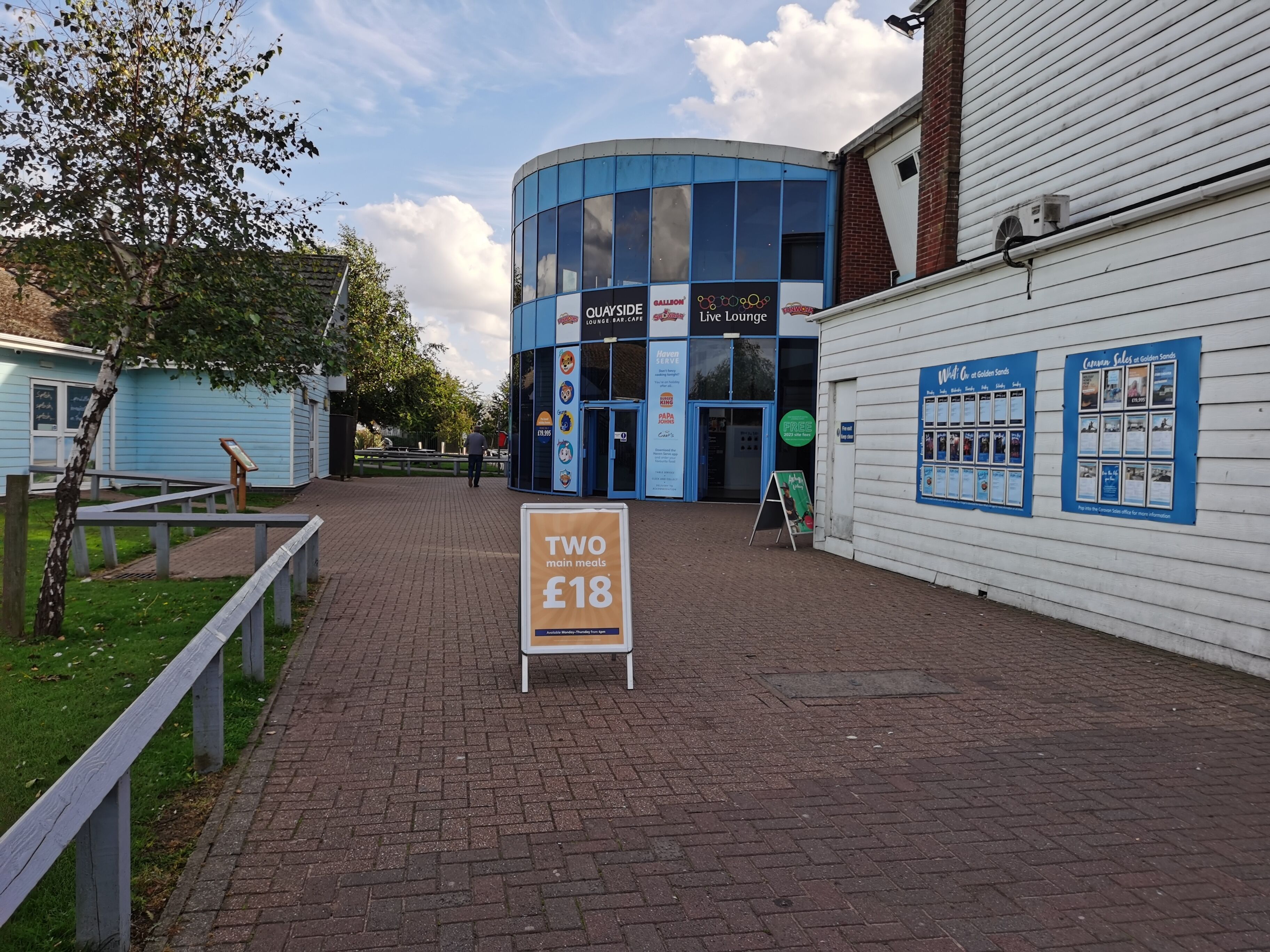 A building with a blue facade, signs for 'Quayside Lounge Bar' and 'Live Lounge', and a sign offering 'Two main meals for £18'.