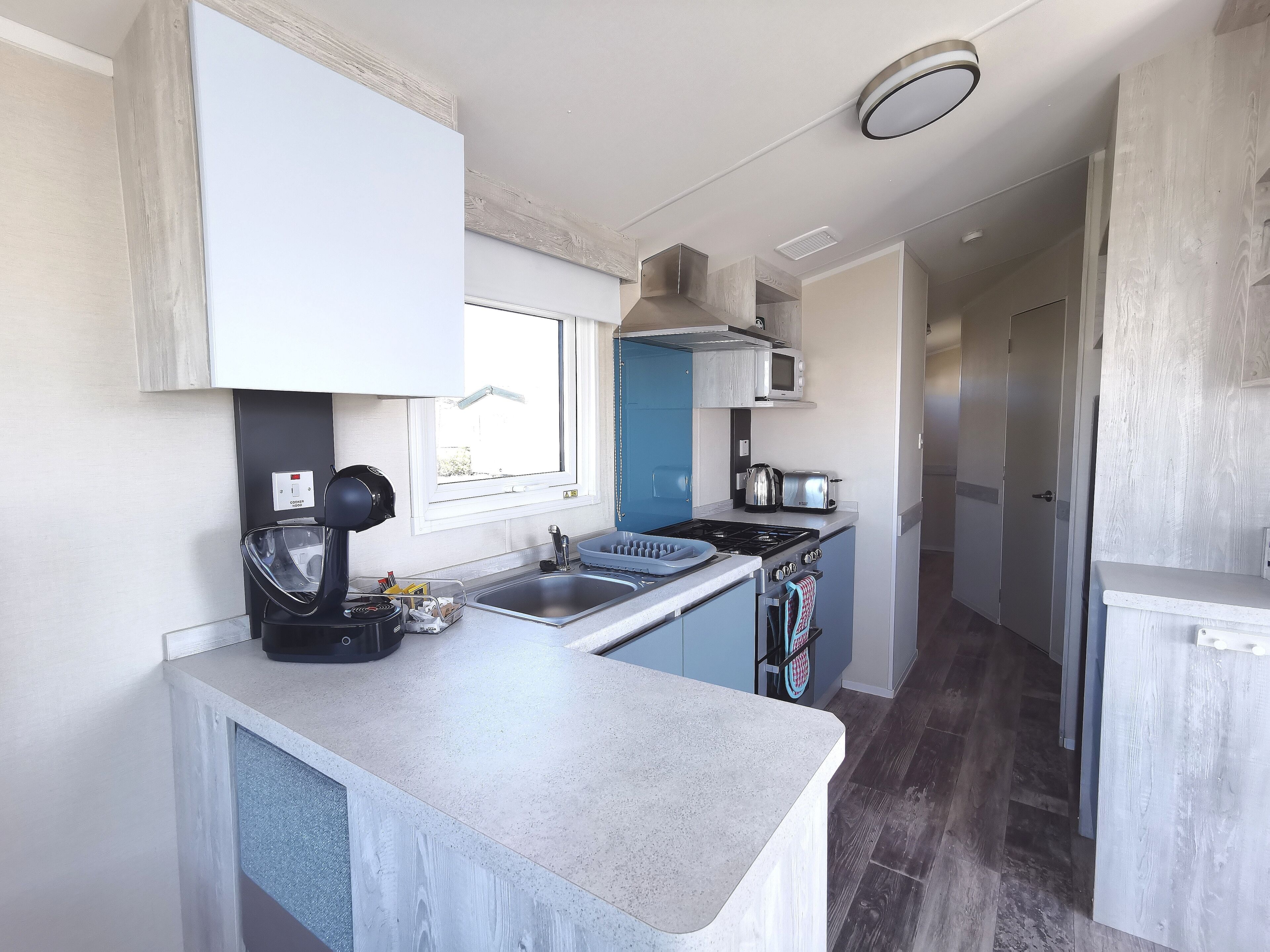 Een moderne keuken met een ingebouwde kookplaat, magnetron en spoelbak.