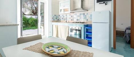 A compact kitchen with a dining table, a stove, and a refrigerator.
