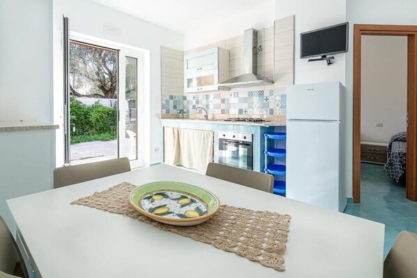 Une cuisine compacte comprenant une table à manger, une cuisinière et un réfrigérateur.