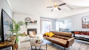 A modern living room with a brown leather sofa, a round coffee table, and a mounted TV. - Cozy & Bright 4BR Home - Perfect for Families (Watauga)