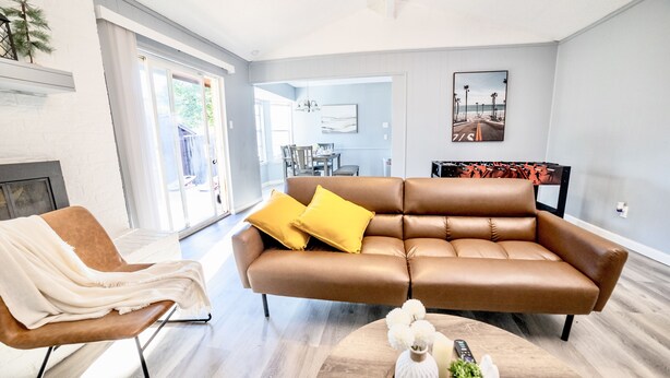 A modern living room with a brown leather sofa, a white armchair, and a wooden coffee table. - Cozy & Bright 4BR Home - Perfect for Families (Watauga)