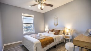 A bedroom with a bed, bedside tables, a desk, and a ceiling fan. - Cozy & Bright 4BR Home - Perfect for Families (Watauga)