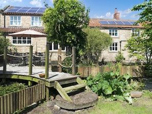 A stone building with a garden, wooden deck, and solar panels on the roof. - 4 bedroom accommodation in Pickering (Pickering)