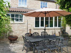 An outdoor patio with a metal table and chairs, a barbecue grill, and a large umbrella. - 4 bedroom accommodation in Pickering (Pickering)
