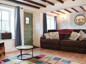A cozy living room with a brown sofa, colorful rug, and a Singer appliance on the window sill. - 4 bedroom accommodation in Pickering (Pickering)