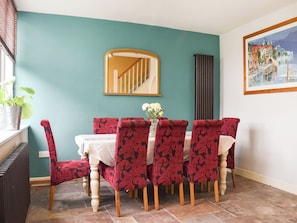 A dining area with teal walls, a wooden table, and red patterned chairs.