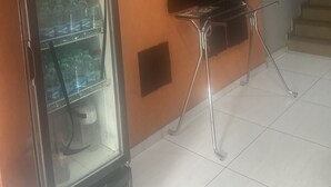 A room with a refrigerator stocked with beverages, a flat-screen TV mounted on the wall, and a staircase in the background. - El Nassr Suits Ltda  (Goiânia)