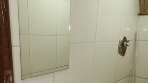 A bathroom with a white sink, toilet, and a glass shower enclosure. - El Nassr Suits Ltda  (Goiânia)