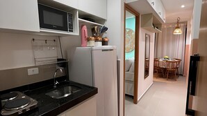 A modern kitchen with white cabinets, a black countertop, a microwave, and a refrigerator. - Cupe Summer 301-Refúgio na Praia-By Use (Ipojuca)