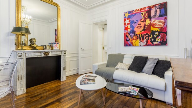A modern living room with a white sofa, a glass coffee table, a fireplace, and a large mirror. - Luxury Près des Champs Elysées (Paris)