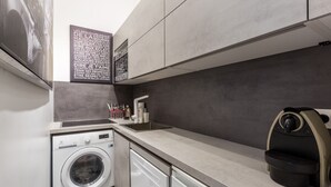 A compact kitchen with a washing machine, a coffee machine, and a sink. - Luxury Près des Champs Elysées (Paris)