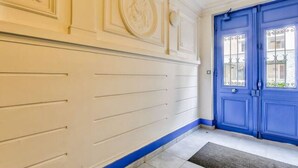 A hallway with a blue door and white walls with decorative molding. - Luxury Près des Champs Elysées (Paris)