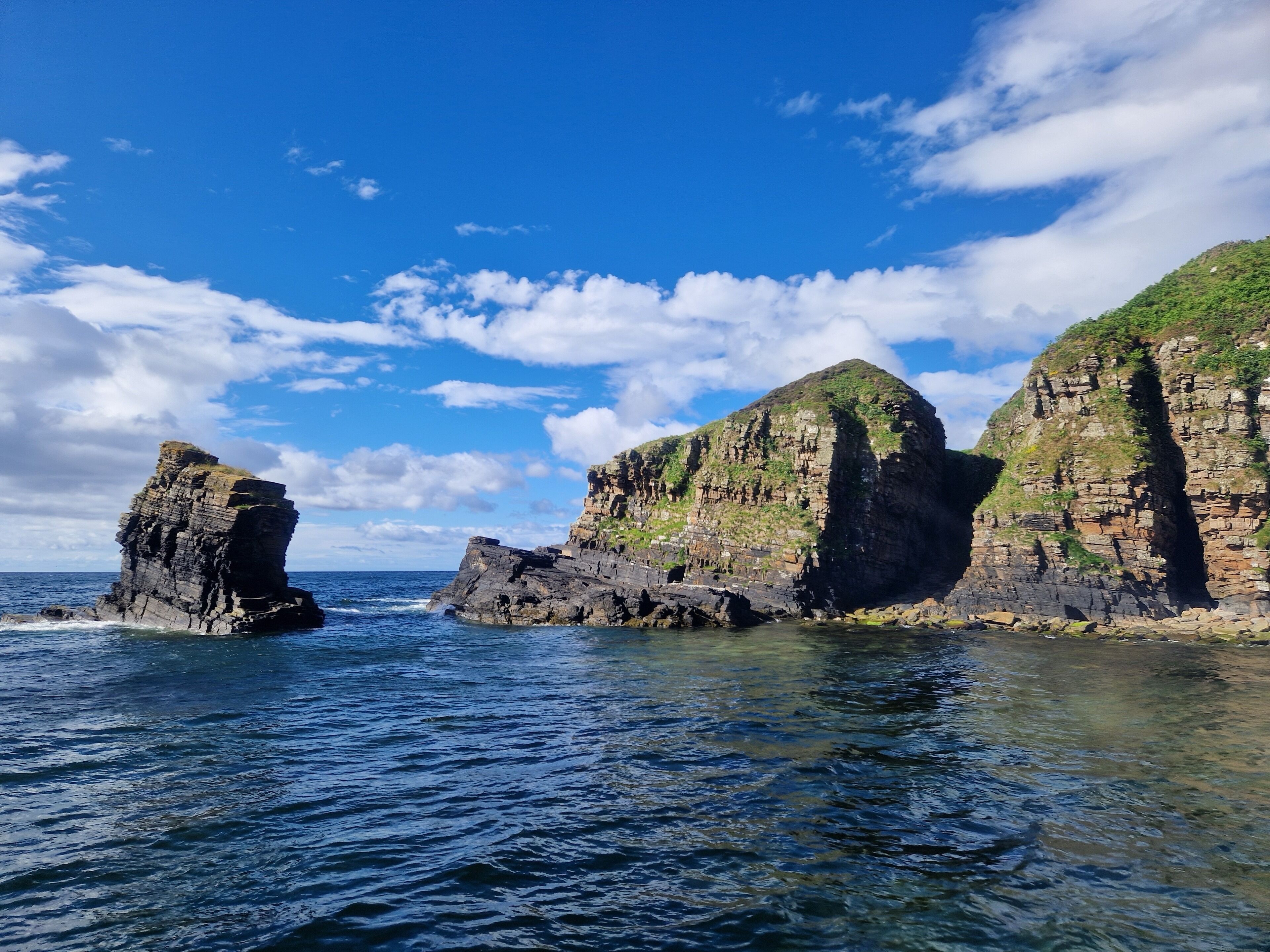 A coastal landscape with rocky cliffs and clear blue water.